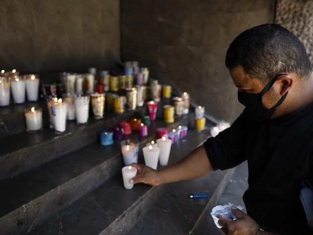 Juan Pablo Rosa Victorin, 34, wears a protective face mask as he lights candles on behalf