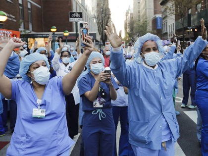 Nurses and medical workers react as police officers and pedestrians cheer them outside Lenox Hill Hospital Wednesday, April 15, 2020, in New York. (AP Photo/Frank Franklin II)