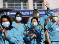 Swedish Medical Center health care workers look on as first responders gathered outside the hospital in support of them in their work against the coronavirus outbreak Thursday, April 16, 2020, in Seattle. First responders across King County planned to stand outside of 15 hospitals in a show of appreciation for …