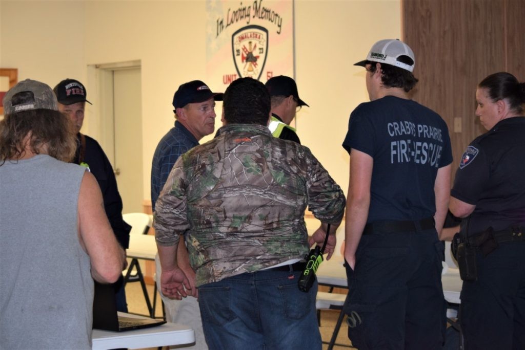 Onalaska Volunteer Fire Department Chief Jay Stutts briefs police and other first responders on tornado rescue operations. (A woman walks with her child after the Onalaska tornado ripped off much of her roof. (Photo: Lana Shadwick/Breitbart Texas)