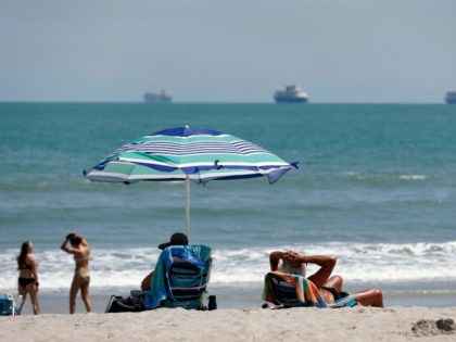 Despite a stay at home policy due to the coronavirus in Florida, beach goers enjoy the sun as cruise ships, without passengers, float offshore Saturday, April 4, 2020, in Cape Canaveral, Fla. Although some of the county beaches remained open, with out parking, many beach goers remained at home. (AP …