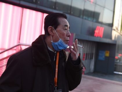 A man lowers his face mask to smoke a cigarette in Beijing on February 17, 2020. - The death toll from China's COVID-19 coronavirus epidemic jumped to 1,770 after 105 more people died, the National Health Commission said on February 17. More than 70,500 have now been infected nationwide by …