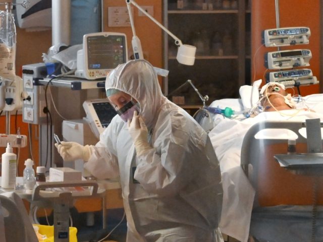 A medical worker wearing a protective gear works by a patient (Rear R) on March 24, 2020 a
