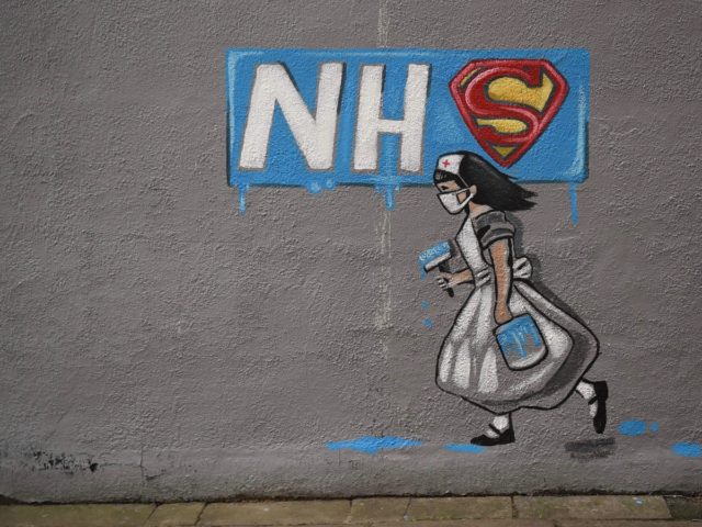 Graffiti depicting the badge of the fictional super heros Superman and Superwoman, and the logo of Britain's National Health Service (NHS) above street art of a nurse, are pictured on a wall in Pontefract, northern England on April 3, 2020, as life in Britain continues during the nationwide lockdown to …
