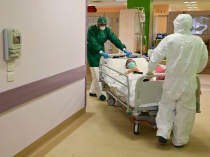 Members of the medical staff carry a patient infected by the novel coronavirus at the High Intensity Medicine department of the Circolo di Varese hospital on April 3, 2020, amid the spread of the epidemic COVID-19. - Italy's three-week lockdown to stop the spread of COVID-19 has been extend through …