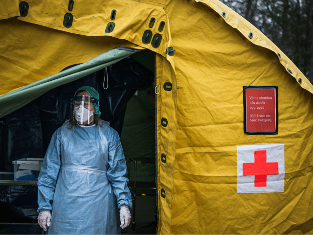 A medical staffer at Sophiahemmet hospital stands at the entrance of a tent for testing an