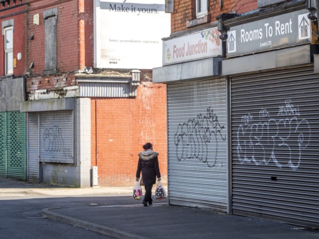 A woman carries shopping past closed shops in Leeds city centre, West Yorkshire on April 14, 2020, as life in Britain continues during the nationwide lockdown to combat the novel coronavirus COVID-19 pandemic. - Britain's economy could shrink by an unprecedented 13 percent this year in the case of a …