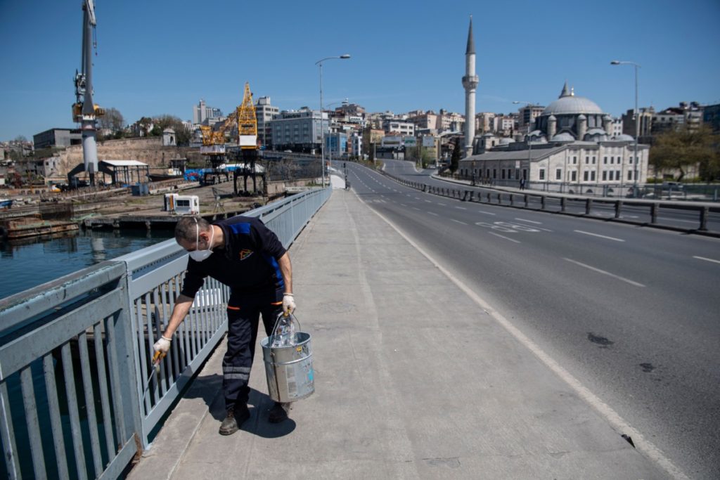 A municipality employee paints fences on Unkapani bridge in Istanbul on April 18, 2020, as Turkish government announced a two-day curfew to prevent the spread of the epidemic COVID-19 caused by the novel coronavirus. (Photo by Ozan KOSE / AFP) (Photo by OZAN KOSE/AFP via Getty Images)