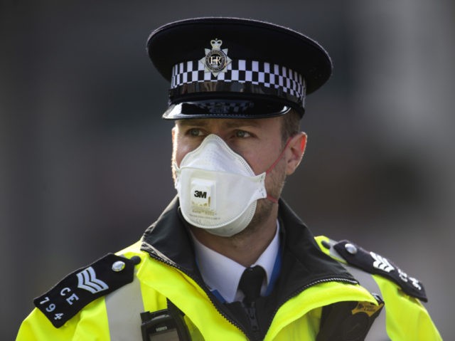 LONDON, ENGLAND - APRIL 09: A police officer in a mask stands guard outside St Thomas&#039