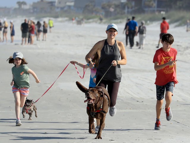 People run on the beach on April 17, 2020 in Jacksonville Beach, Florida. Jacksonville Mayor Lenny Curry announced Thursday that Duval County's beaches would open at 5 p.m. but only for restricted hours and can only be used for swimming, running, surfing, walking, biking, fishing, and taking care of pets. …