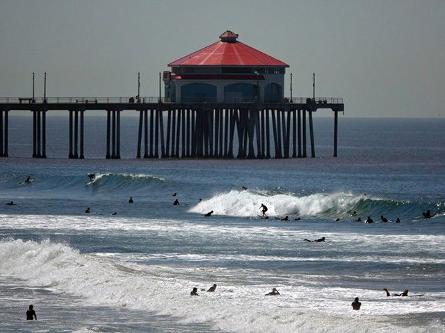 HUNTINGTON BEACH, CA - APRIL 22: Surfers ride waves in front of the Huntington Beach pier
