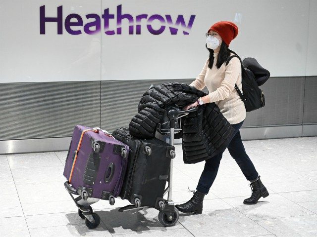 Passengers wear face masks as the push their luggage after arriving from a flight at Terminal 5 of London Heathrow Airport in west London on January 28, 2020. - Chinese President Xi Jinping said Tuesday the country was waging a serious fight against the "demon" coronavirus outbreak and pledged transparency …
