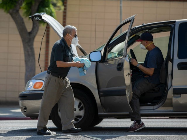 Motorists wear face masks as they work on a vehicle downtown Los Angeles Wednesday, April