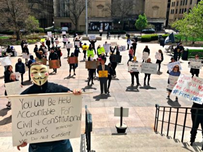 About 75 people wearing masks and carrying signs protest outside the Ohio Statehouse on Th