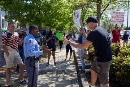 Protesters from a grassroots organization called REOPEN NC argue with a Raleigh police officer during a demonstration against the North Carolina coronavirus lockdown at a parking lot adjacent to the North Carolina State Legislature in Raleigh, North Carolina, on April 14, 2020. - The group was demanding the state economy …
