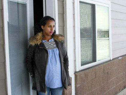 In this April 13, 2020, photo, Kulule Amosa steps out of the apartment she shares with her husband who works at the Smithfield Foods pork processing plant in Sioux Falls, S.D. He tested positive for the coronavirus this week after an outbreak at the plant. (AP Photo/Stephen Groves)