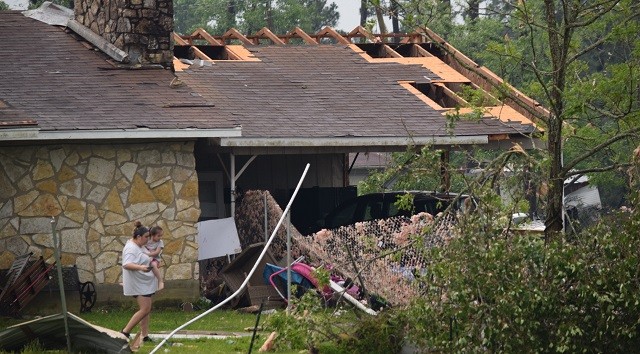 A woman walks with her child after the Onalaska tornado ripped off much of her roof. (Photo: Lana Shadwick/Breitbart Texas)