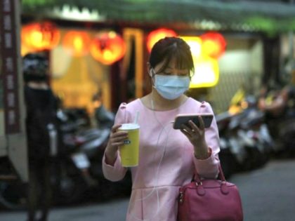 aptopix-virus-outbreak-taiwan-woman-protective-mask-balances-sized-cup-watching-smart-pho-640x448