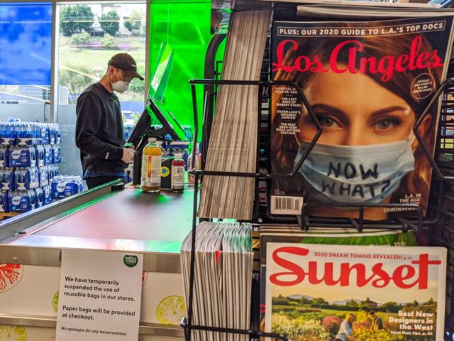 A patron wears a cap, face mask and gloves while shopping at the 365 Whole Foods Market in