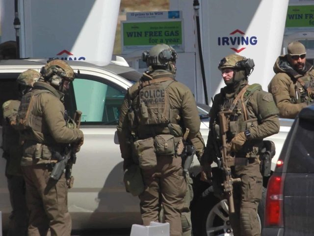 Members of the Royal Canadian Mounted Police (RCMP) tactical unit confer after the suspect