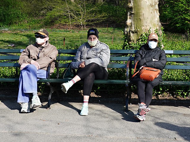 NEW YORK, NEW YORK - APRIL 11: People wearing protective masks sit on a bench in Central P