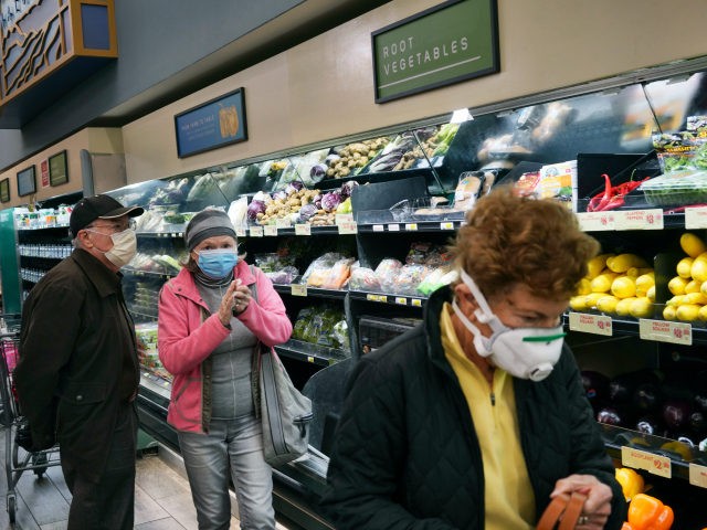 In this March 20, 2020, file photo, customers wear protective masks while shopping for gro