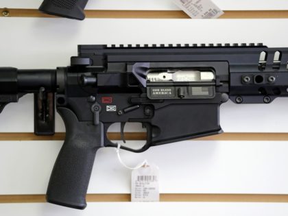 FILE - In this photo taken Oct. 2, 2018, a semi-automatic rifle, with "God Bless America" imprinted on it, is displayed for sale on the wall of a gun shop in Lynnwood, Wash. A dozen county sheriffs in Washington state are refusing to enforce restrictions on semi-automatic rifles that voters …