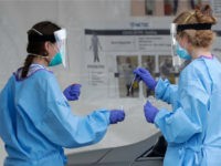 Healthcare worker put a test swab into a container after swabbing the driver at a newly opened drive-through COVID-19 testing site at the Miami-Dade County Youth Fair & Exposition center, Wednesday, April 8, 2020, in Miami. (AP Photo/Wilfredo Lee)