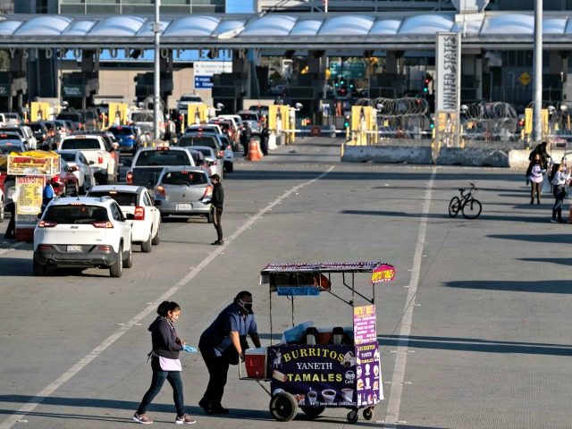 Street vendors wear face masks as a preventive measure to avoid the spread of COVID-19 at the San Ysidro crossing in Tijuana on April 23, 2020. (Credit: Guillermo Arias / AFP / Getty Images)