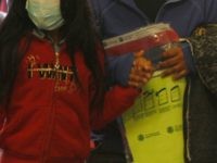 A woman carries a property bag issued by Customs and Border Protection while holding the hand of a girl wearing a mask as they arrive at a mandatory immigration court hearing on Monday, March 16, 2020, in El Paso, Texas. The migrants, who must wait in Ciudad Juarez, Mexico, wore …