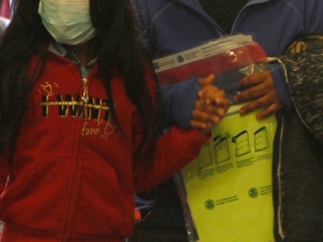 A woman carries a property bag issued by Customs and Border Protection while holding the h