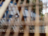 Police officers keep guard near a barricade after the locality was sealed following cases of COVID-19 in the area, in Worli village, Mumbai, India, Tuesday, March 31, 2020. India is adding more resources to tackle its increase in coronavirus cases by announcing that private hospitals may be requisitioned to help …