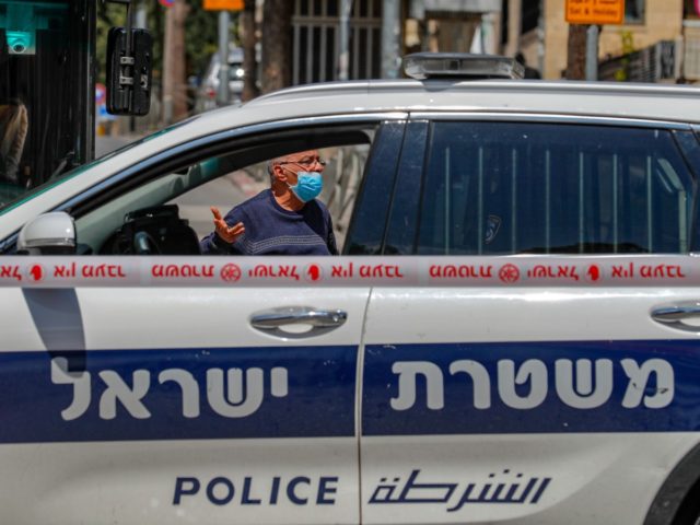 An Israeli man gestures from behind a police car, stationed at the entrance of the Mea Shearim neighbourhood in Jerusalem on April 12, 2020, during the novel coronavirus pandemic crisis. (Photo by AHMAD GHARABLI / AFP) (Photo by AHMAD GHARABLI/AFP via Getty Images)