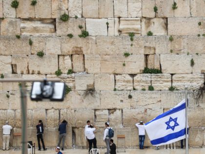 People pray at the nearly deserted Western Wall, Judaism's holiest prayer site, after Israel has imposed some of the world's tightest restrictions to contain COVID-19 coronavirus disease, in Jerusalem on March 12, 2020. - Israel imposed a two-week quarantine on all travellers entering the country, almost stopping tourism and limiting …