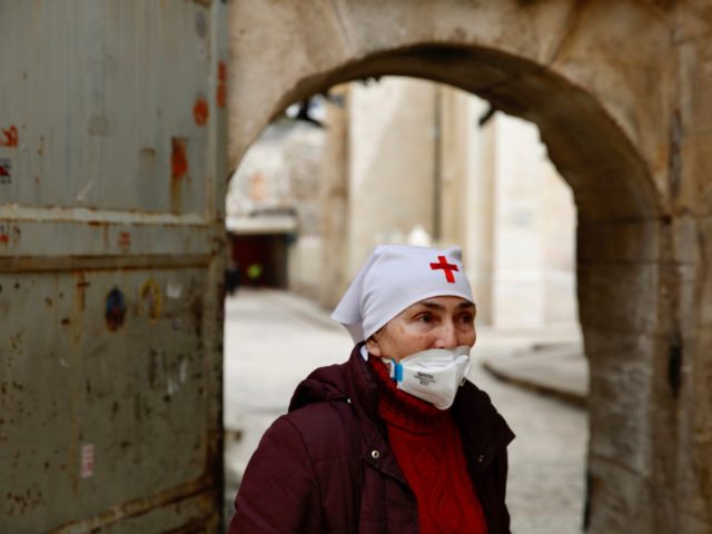 A nun wears a mask to help prevent the spread of the coronavirus next to the closed Church of the Holy Sepulchre, a place where Christians believe Jesus Christ was buried as a palm hangs on the door in Jerusalem's old city, Sunday, April 5, 2020. The traditional Palm Sunday …
