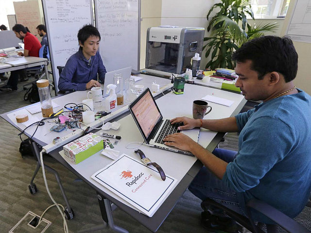 In this Thursday, June 30, 2016 photo, Babson College graduate school alumnus Abhinav Sureka, of Mumbai, India, right, types in his work space at the college in Wellesley, Mass. Some U.S. colleges are starting programs to help their alumni get visas through what critics say is a legal loophole. Foreign …