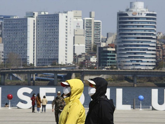 People wearing face masks to help protect against the spread of the new coronavirus walk at a park in Seoul, South Korea, Wednesday, April 8, 2020. The new coronavirus causes mild or moderate symptoms for most people, but for some, especially older adults and people with existing health problems, it …