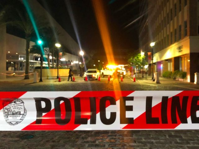 This photo shows a police car behind police tape blocking a street leading to the Jacksonville Landing area in downtown Jacksonville, Florida, August 26, 2018, where three people were killed, including the gunman, and 11 others wounded. - Two people were killed and 11 others wounded on August 26 when …
