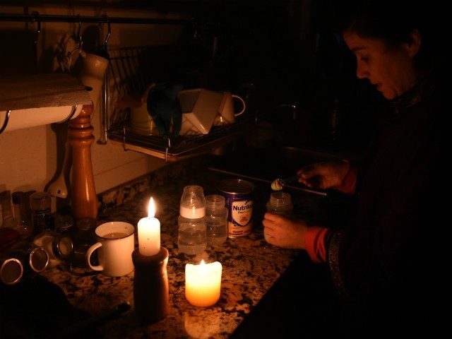 TOPSHOT - A woman prepares milk bottles using candles at her home in Montevideo on June 16, 2019 during a power cut. - A massive outage blacked out Argentina and Uruguay Sunday, leaving both South American countries without electricity, power companies said. (Photo by MIGUEL ROJO / AFP) (Photo credit …