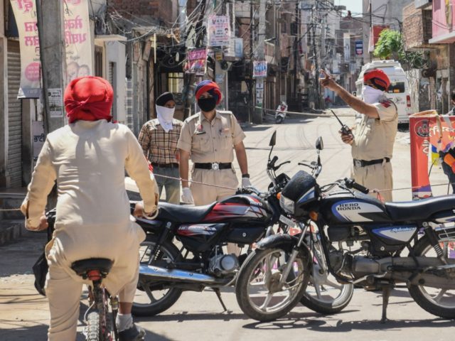 Police personnel stand guard as they close a street near the location of the residence of