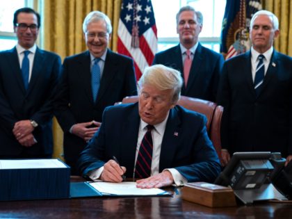 FILE - In this March 27, 2020 file photo, President Donald Trump signs the coronavirus stimulus relief package, at the White House in Washington, as from left, Treasury Secretary Steven Mnuchin, Senate Majority Leader Mitch McConnell of Ky., House Minority Kevin McCarthy of Calif., and Vice President Mike Pence, look …
