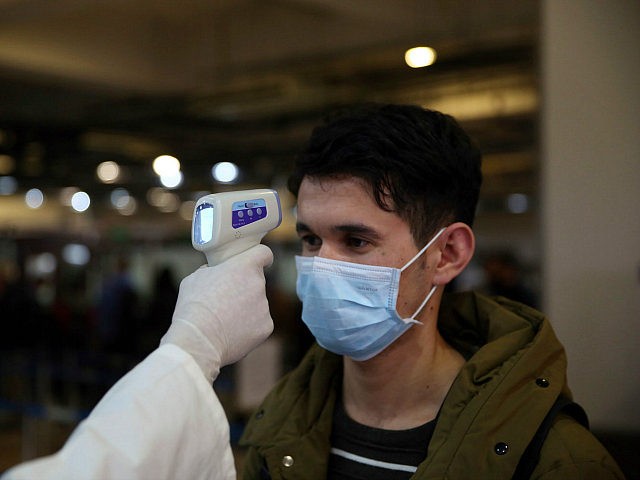 An Afghan health worker takes the temperature of a passenger as a preventive measure for C