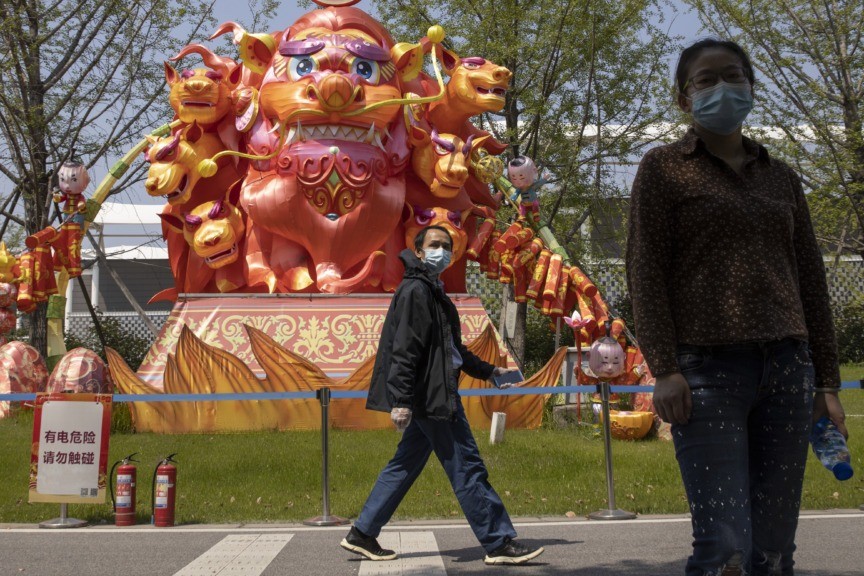 Residents wearing masks against the coronavirus walk past lantern sculptures at a park in Wuhan in central China's Hubei province on Thursday, April 9, 2020. Chinese authorities ended the lockdown of Wuhan on Wednesday, allowing people to move about and leave the city for the first time in 76 days. (AP Photo/Ng Han Guan)