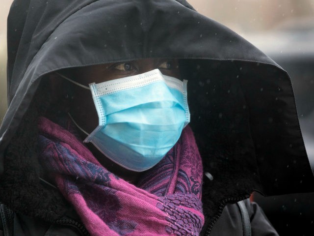 A woman wears a protective mask outside a supermarket in Chelsea, Mass., Friday, April 3,