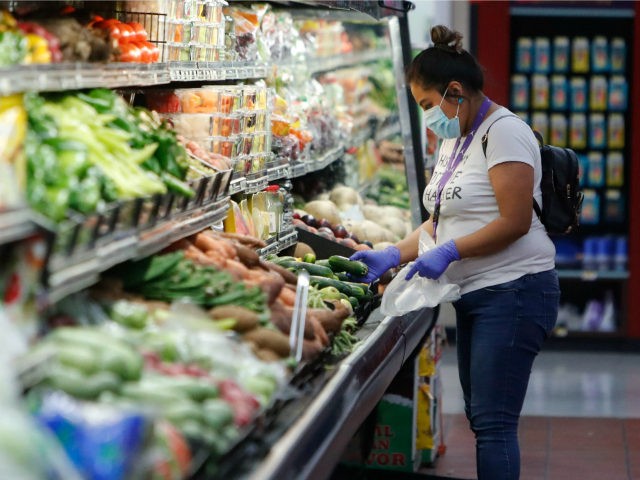 A woman wears a mask amid social distancing during the COVID-19 outbreak while shopping the well stocked produce section at El Rancho grocery store in Dallas, Thursday, March 26, 2020. For most people, the new coronavirus causes mild or moderate symptoms, such as fever and cough that clear up in …