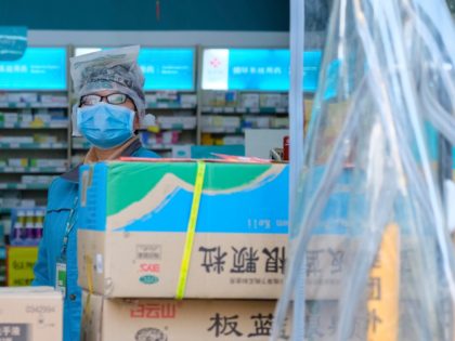 A clerk wearing a face mask and a plastic bag stands in a pharmacy in Wuhan in central China's Hubei Province, Friday, Jan. 31, 2020. The U.S. advised against all travel to China as the number of cases of a worrying new virus spiked more than tenfold in a week, …