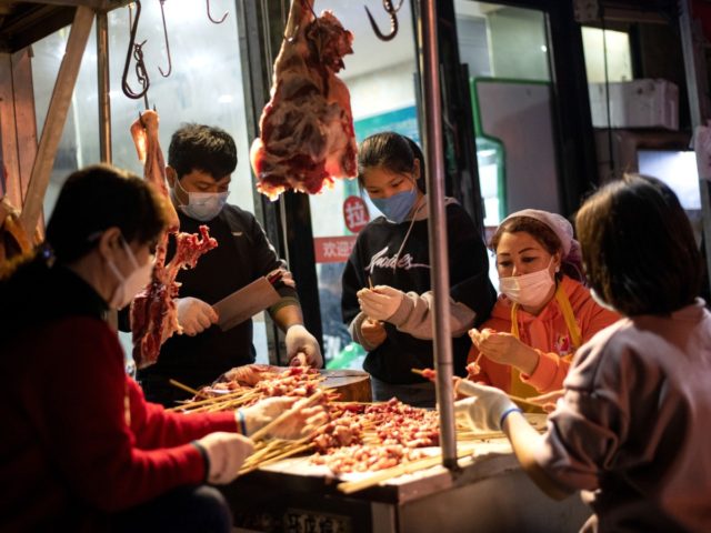 Workers wearing facemasks make a barbecue at a market in Wuhan, in China's central Hubei province on April 4, 2020. - China came to a standstill on Saturday to mourn patients and medical staff killed by the coronavirus, as the world's most populous country observed a nationwide three-minute silence. (Photo …