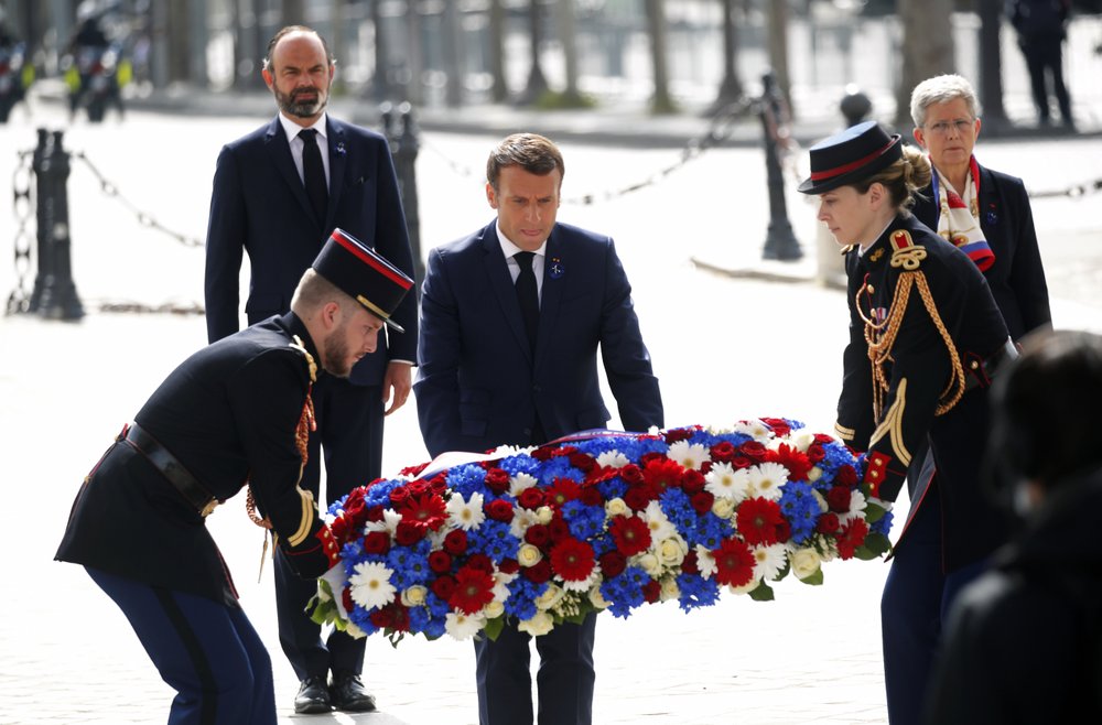 French President Emmanuel Macron lays a wreath of flowers during a ceremony to mark the 75th anniversary of the World War II victory over Nazi Germany, at the Arc de Triomphe in Paris, Friday May 8, 2020. The ceremony was marked by the absence of public and complete silence in the streets of central Paris, as all gatherings are banned under France's confinement measures. At left behind is French Prime Minister Edouard Philippe. (Charles Platiau/Pool via AP)