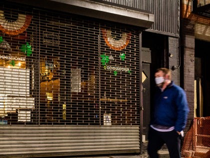 A man walks in front of a New York City bar wearing a cloth mask. Gov. Andrew Cuomo (D-NY) said Monday that he is in favor of fining New Yorkers for not wearing masks in public to combat the spread of the Chinese coronavirus.