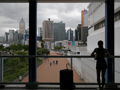 In this June 10, 2019, photo, a woman stands near the skyline of Hong Kong at Central, bus